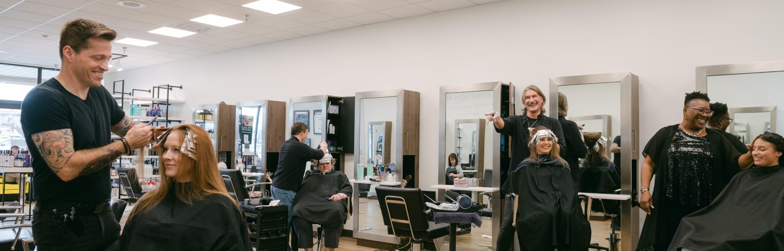 Stylists talking and working on customer's hair.