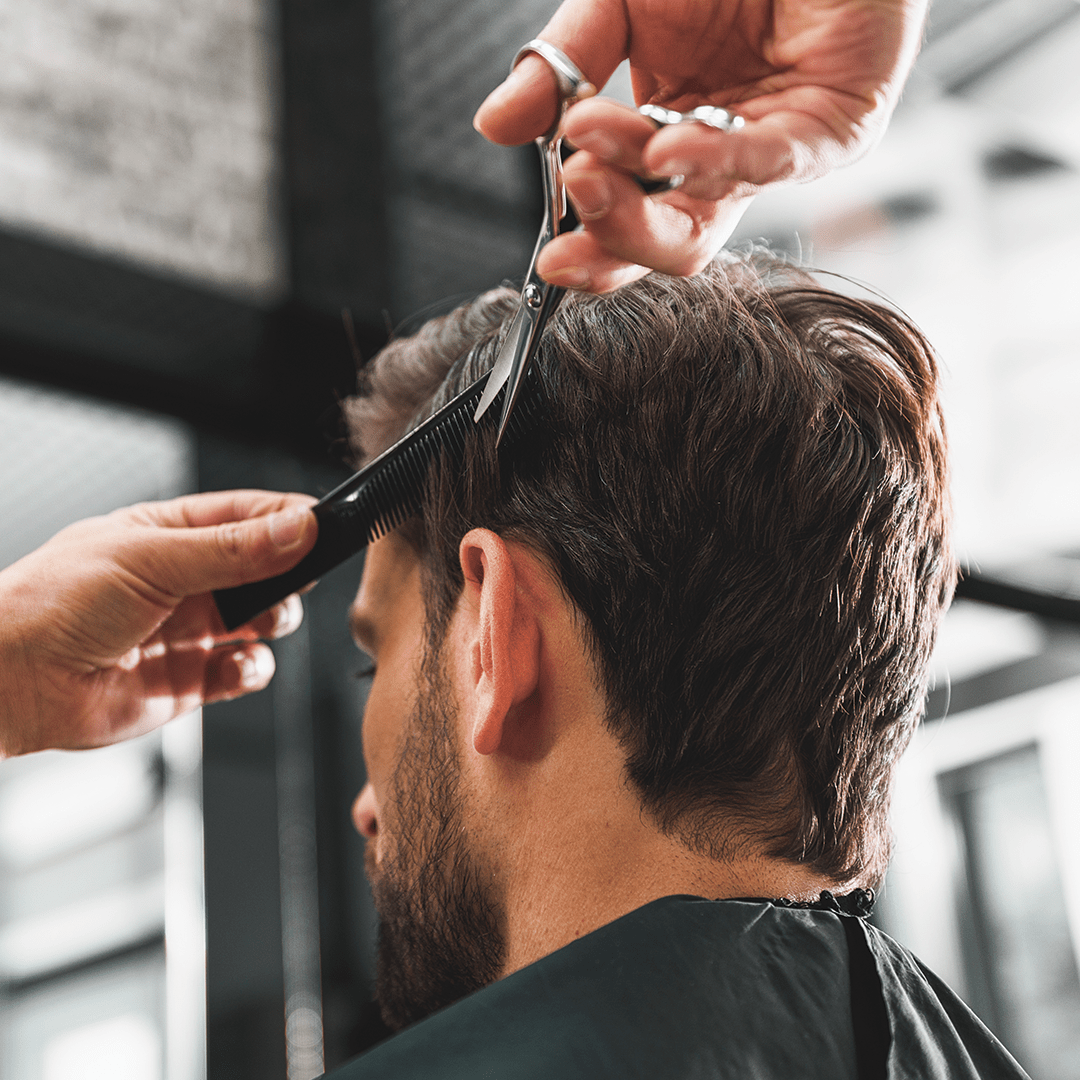 Stylist trimming a client’s hair during a routine haircut maintenance appointment
