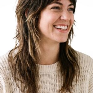 Smiling woman with shaggy wolf cut hairstyle and curtain bangs