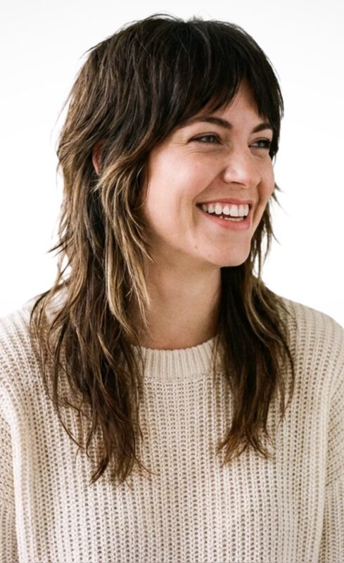 Smiling woman with shaggy wolf cut hairstyle and curtain bangs